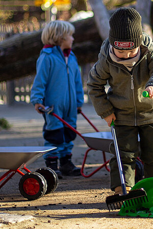Kindergeburtstag im Tierpark Hellabrunn Ein Kind mit einer grünen Schaufel sammelt Tierkot ein.