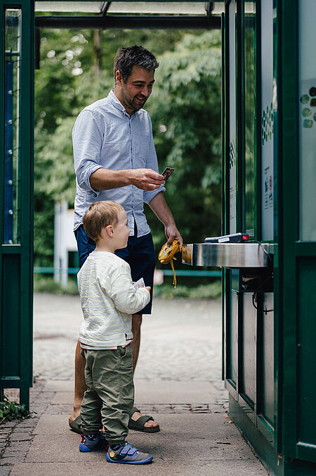 Ein Vater mit seinem Sohn bezahlt an der Kasse seine Tickets